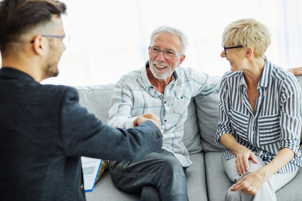 Happy senior old family couple clients make financial insurance estate business deal handshake agent lawyer, satisfied mature customers shake hand meeting bank manager agree on investment contract, contract signing